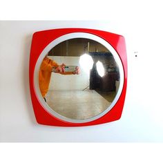 a person taking a selfie in front of a red and white wall mounted mirror