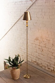 a floor lamp sitting on top of a wooden table next to a potted plant