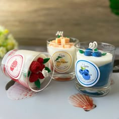 three candles are sitting on a table next to seashells