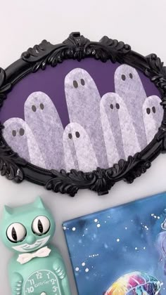 there is a mirror with ghost faces on it next to some other items and a cat figurine