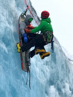 two people climbing up the side of a snow covered mountain