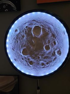 a clock that is on the wall with some lights in it's center and an image of saturn behind it