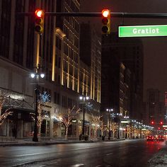 a city street at night with traffic lights and christmas trees on the side of the road