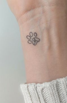 a small paw tattoo on the wrist is shown in black ink, with an animal's paw drawn across it