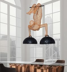 a dining room table with two chairs and a sculpture hanging from it's ceiling