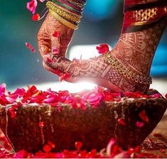 the feet of a woman with henna and flowers on her feet, in front of a bowl full of petals