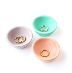 three different colored bowls with gold rings in them