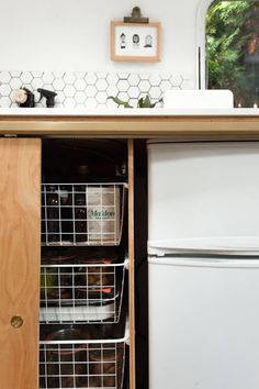 an open cabinet in the kitchen with two baskets on it's bottom and one door opened