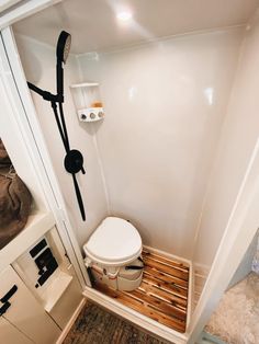 a bathroom with a toilet, shower head and wooden pallets on the floor in it