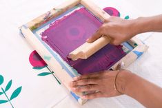 a woman is using a wooden frame to paint an art project with acrylic paint