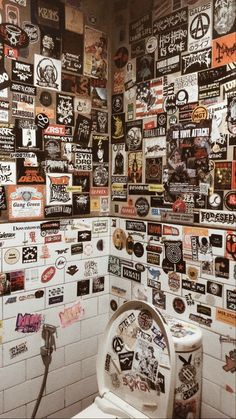 a white toilet sitting next to a wall covered in stickers