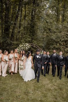 a group of people standing next to each other in front of trees and bushes with flowers