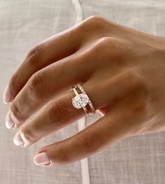 a woman's hand with a diamond ring on her left hand and the other hand holding an engagement ring