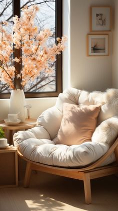 a white chair sitting in front of a window next to a vase filled with flowers