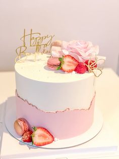 a white cake with strawberries on it and a happy birthday sign in the background