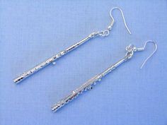 two silver tone earrings with beads and chains hanging from them on a blue cloth background