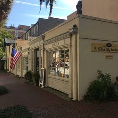 an american flag is hanging on the side of a building in front of a sidewalk