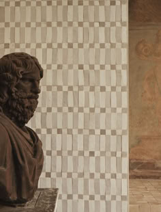 a bust of a man sitting on top of a bench in front of a wall