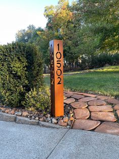 a sign that is on the side of a road in front of some grass and trees