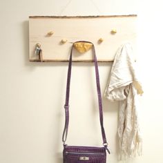 a purse hanging on a wall next to a coat rack with hooks and a scarf