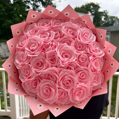 a person holding a large bouquet of pink roses