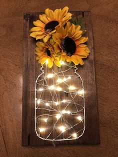 a mason jar with sunflowers and fairy lights is displayed on a wooden board