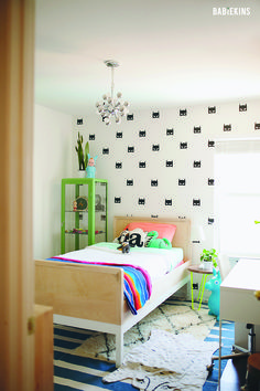 a bed room with a neatly made bed next to a wallpapered wall and a rug on the floor