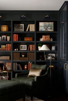 a living room filled with lots of bookshelves next to a couch and lamp