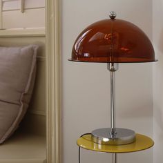 a table lamp sitting on top of a yellow shelf next to a bed with pillows