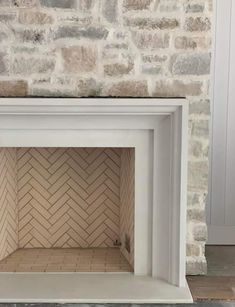 an empty fireplace in front of a brick wall with white paint on the top and bottom