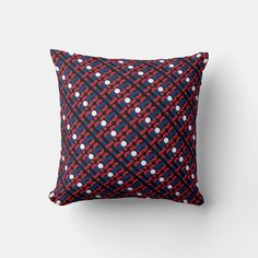 a red, white and blue pillow with circles on it in front of a gray wall