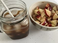 a bowl of food next to a jar of ice tea on a table with a straw in it