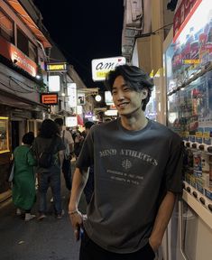 a man standing in front of a store on the side of a street at night