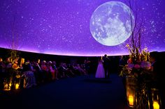 a couple standing under a purple sky filled with stars and the moon in the distance