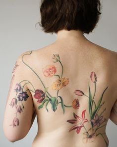 a woman with tattoos on her back and flowers painted on the side of her body