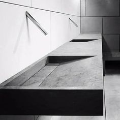 black and white photograph of an empty bench in a public place with no one around