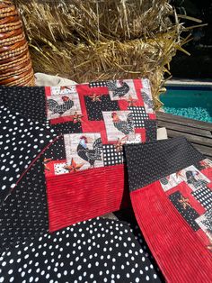 three black and red quilted pillows sitting on top of a wooden deck next to a swimming pool