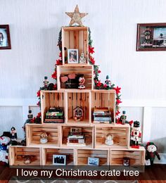 a christmas tree made out of wooden crates with pictures on the top and bottom shelf