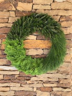 a green wreath hanging on a stone wall