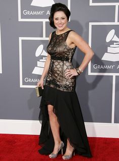 a woman in a black and gold dress on the red carpet at an awards event