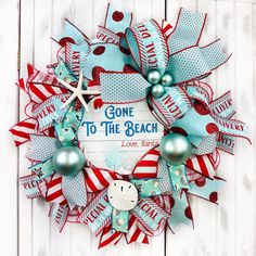 a wreath that says gone to the beach with ornaments around it on a white wooden background