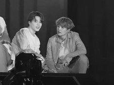 black and white photo of three young men sitting next to each other on a table