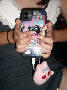 a person holding a cell phone in their hand with an animal keychain attached to it