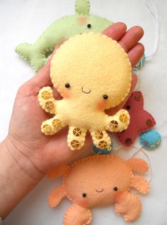 a hand holding three small stuffed animals