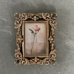 an old fashioned frame with a flower in it on the wall next to a stone floor