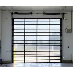 an open garage door with black bars on the side and windows in the back ground