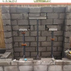 a wall made out of cinder blocks with pipes running through it and two buckets on the side