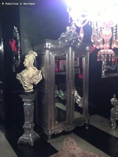 an ornate mirrored cabinet in a black room with chandelier and mirror on the wall