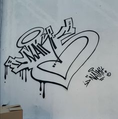 graffiti written on the side of a white wall next to a box with a cardboard box in front of it