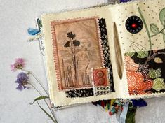 an open book with flowers and buttons on the pages is sitting next to a flower vase